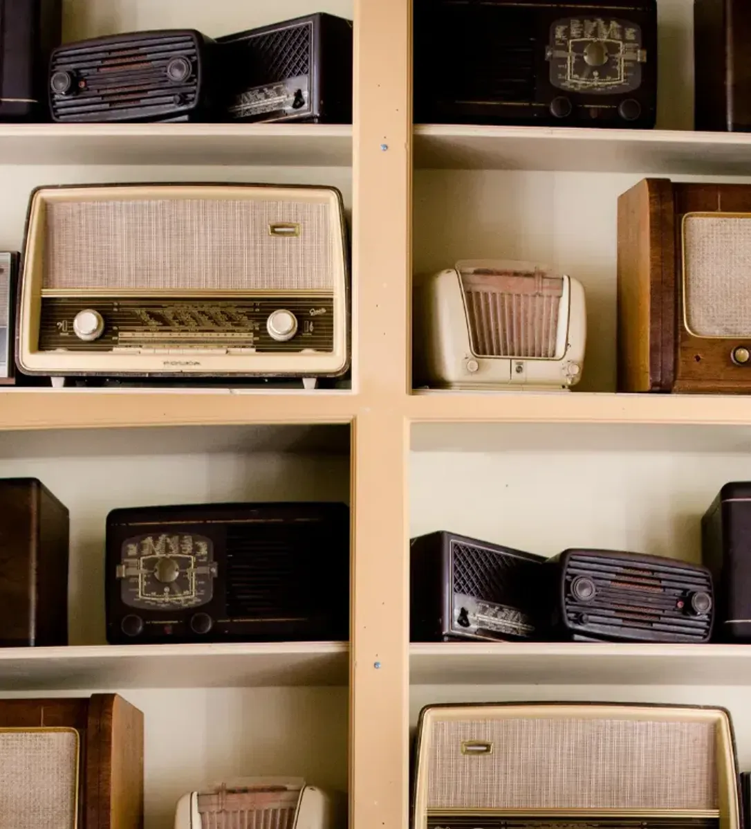 A shelf filled with a variety of old radios.