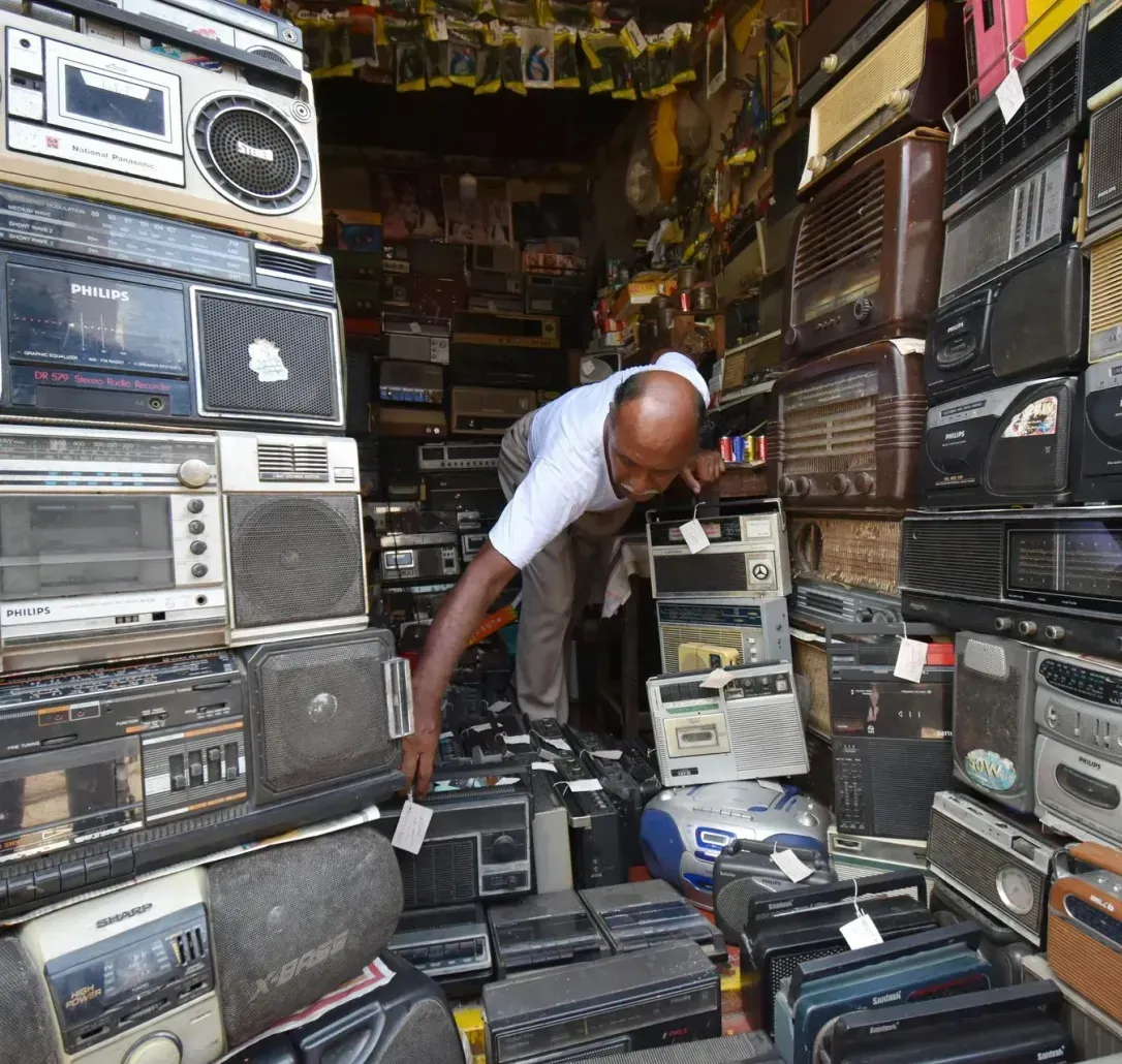 A man is standing in front of a stack of old radios.
