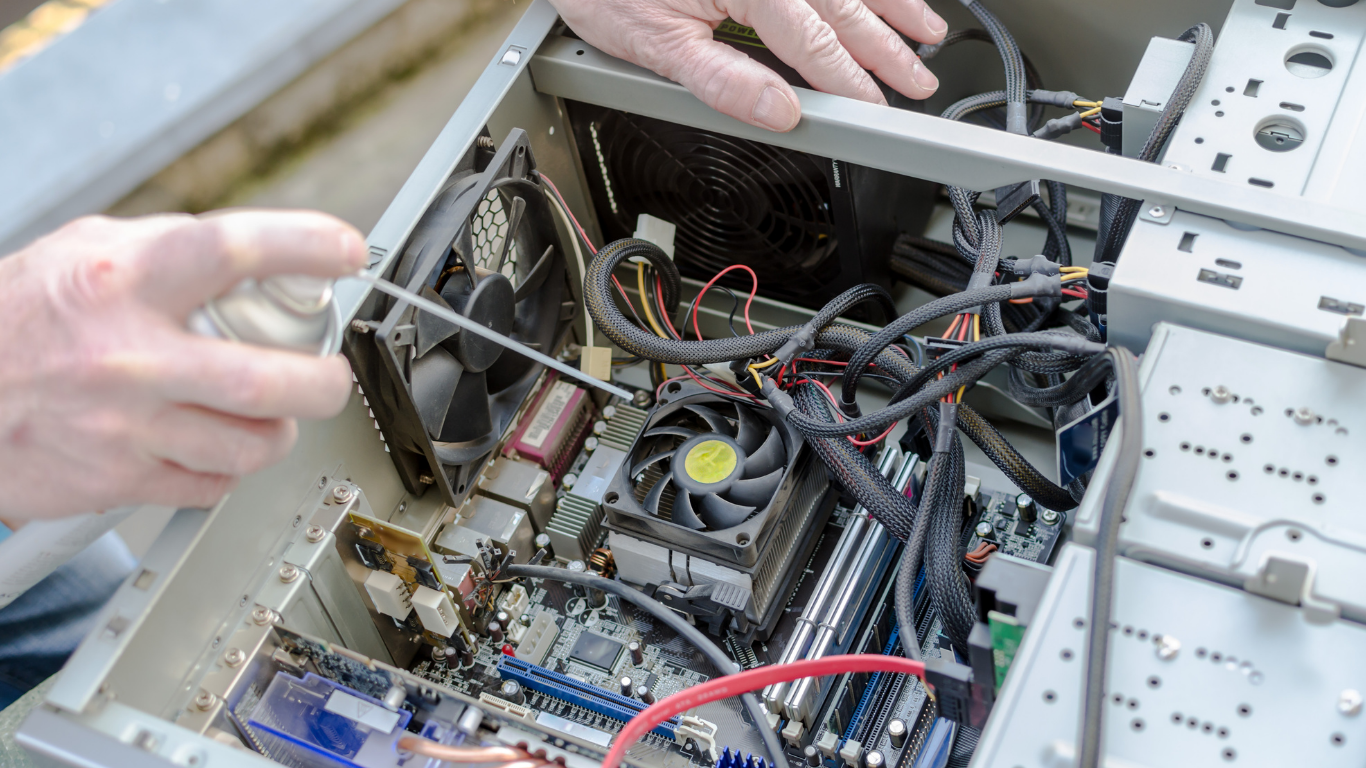 A person is cleaning a computer with a spray bottle.