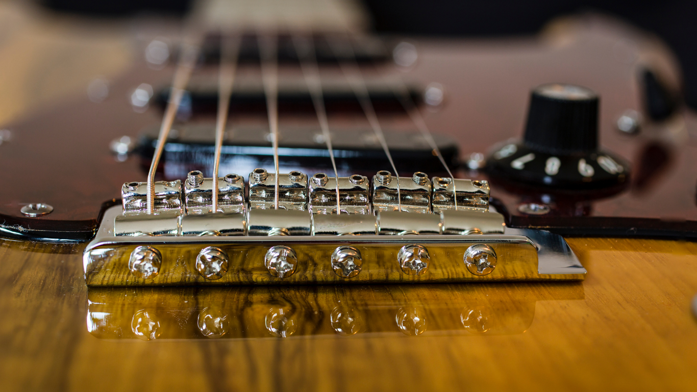 A close up of a guitar bridge on a wooden table.