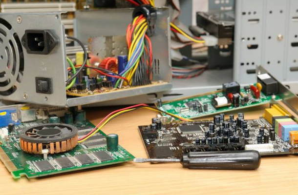 A computer is being repaired on a wooden table.