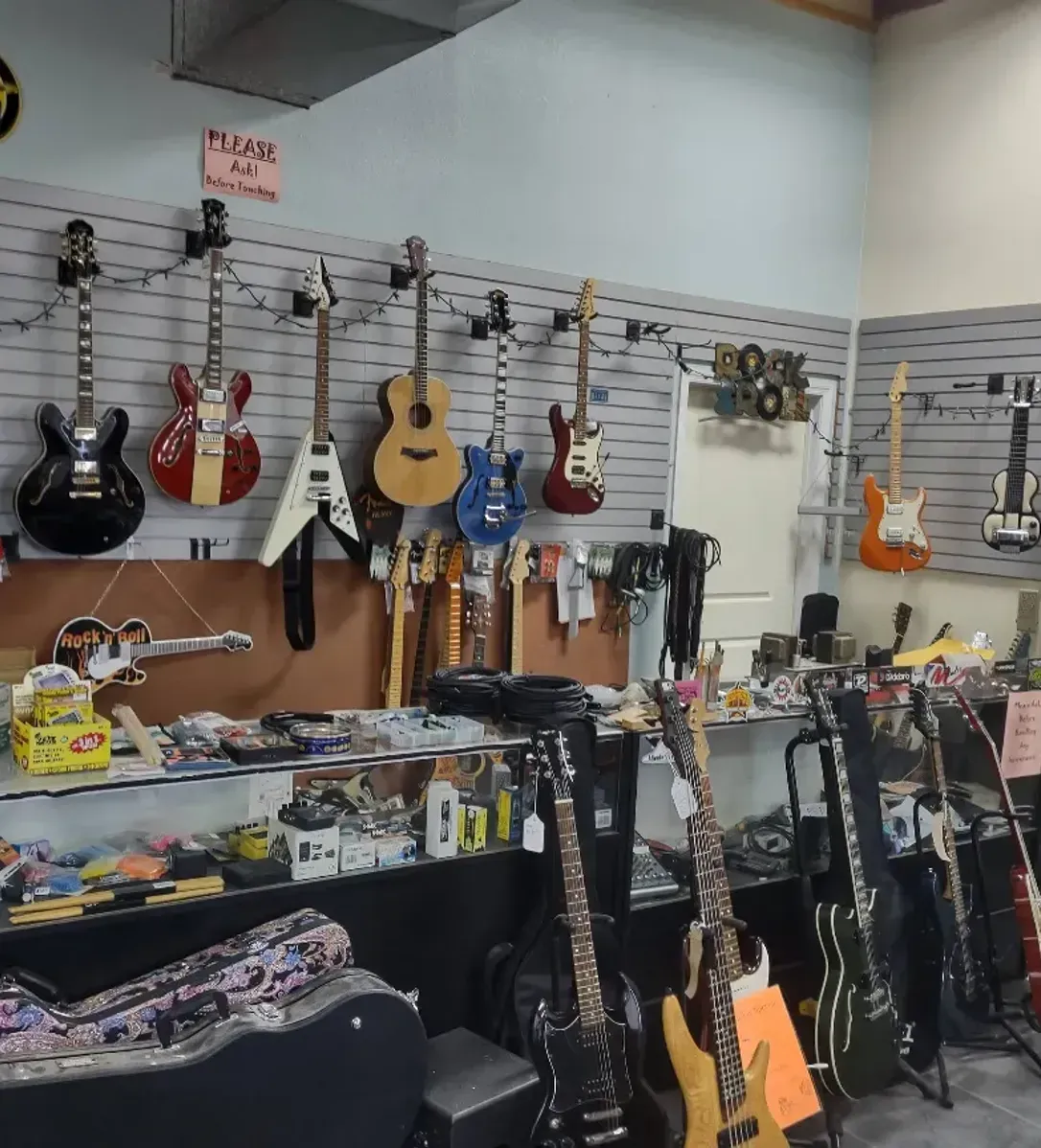 A room filled with lots of guitars hanging on the wall.