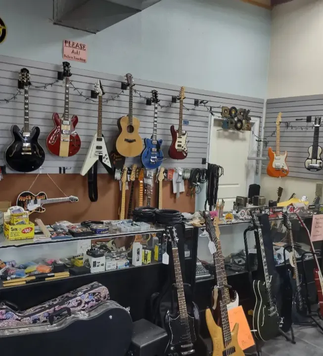 A room filled with lots of guitars hanging on the wall.