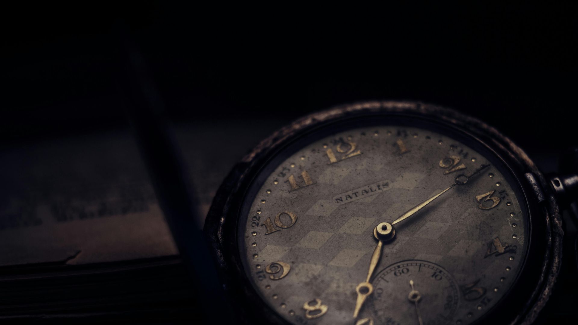 A close up of an old pocket watch in the dark.