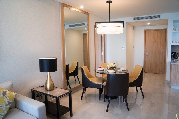 Un comedor moderno con una mesa redonda, cuatro sillas bicolor, una lámpara colgante 