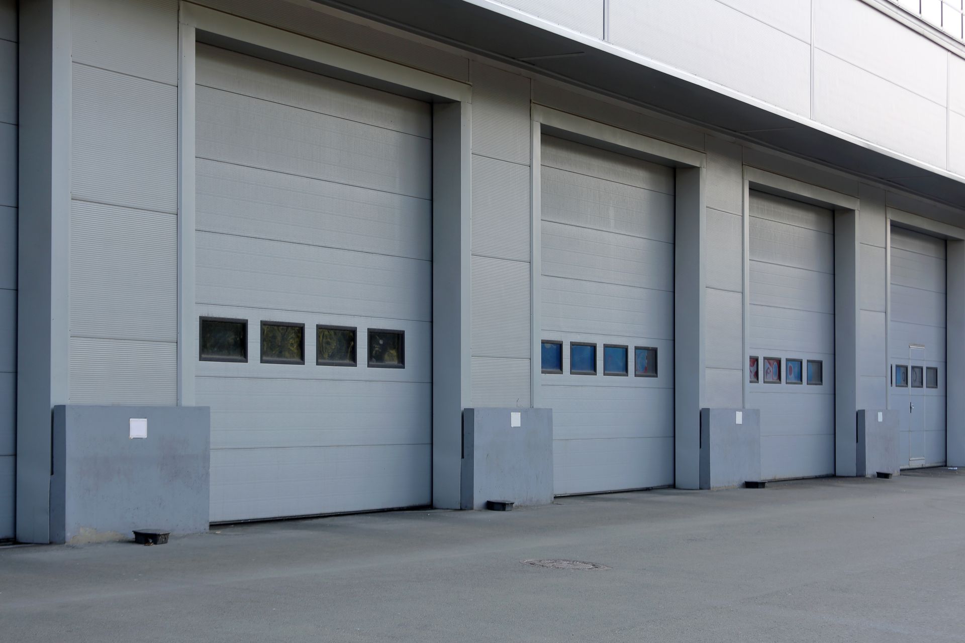 Two white garage doors on a tan house exterior