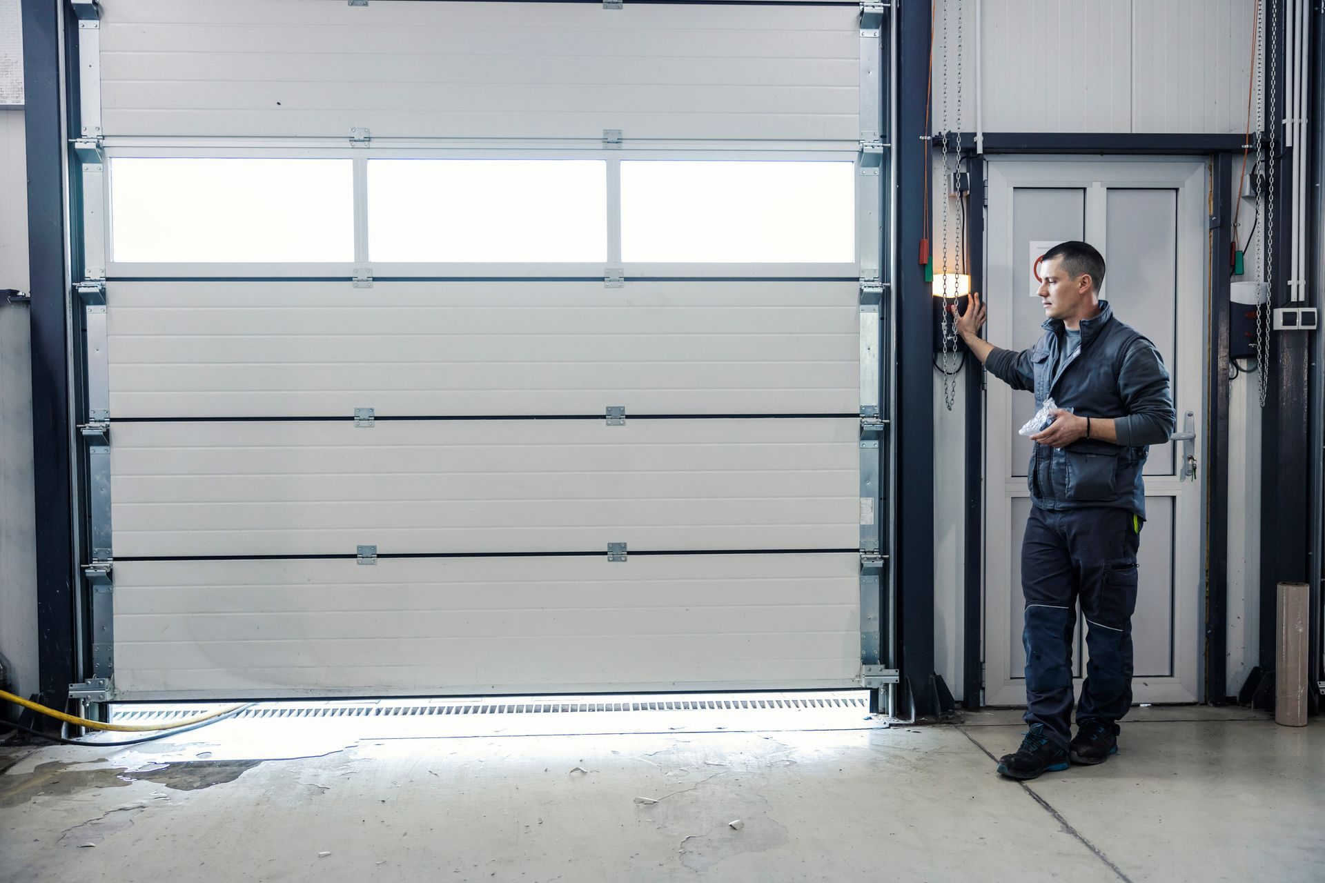 Technician standing beside a large industrial garage door in a warehouse.
