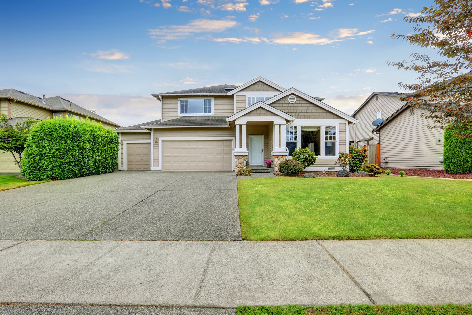 Suburban two-story house with a two-car garage, green lawn, and a clear sky front yard