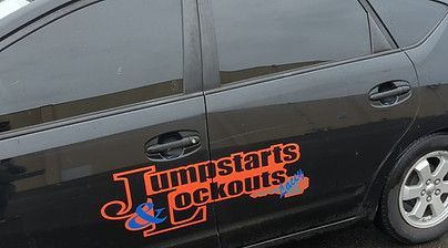 A black car with a sticker on the side that says jumpstarts and lockouts.