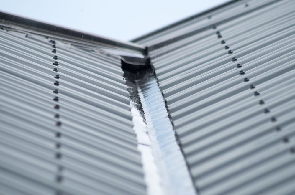 A Close Up of a Metal Roof With a Gutter on It — Apex Roofing Group in Byron Bay, NSW