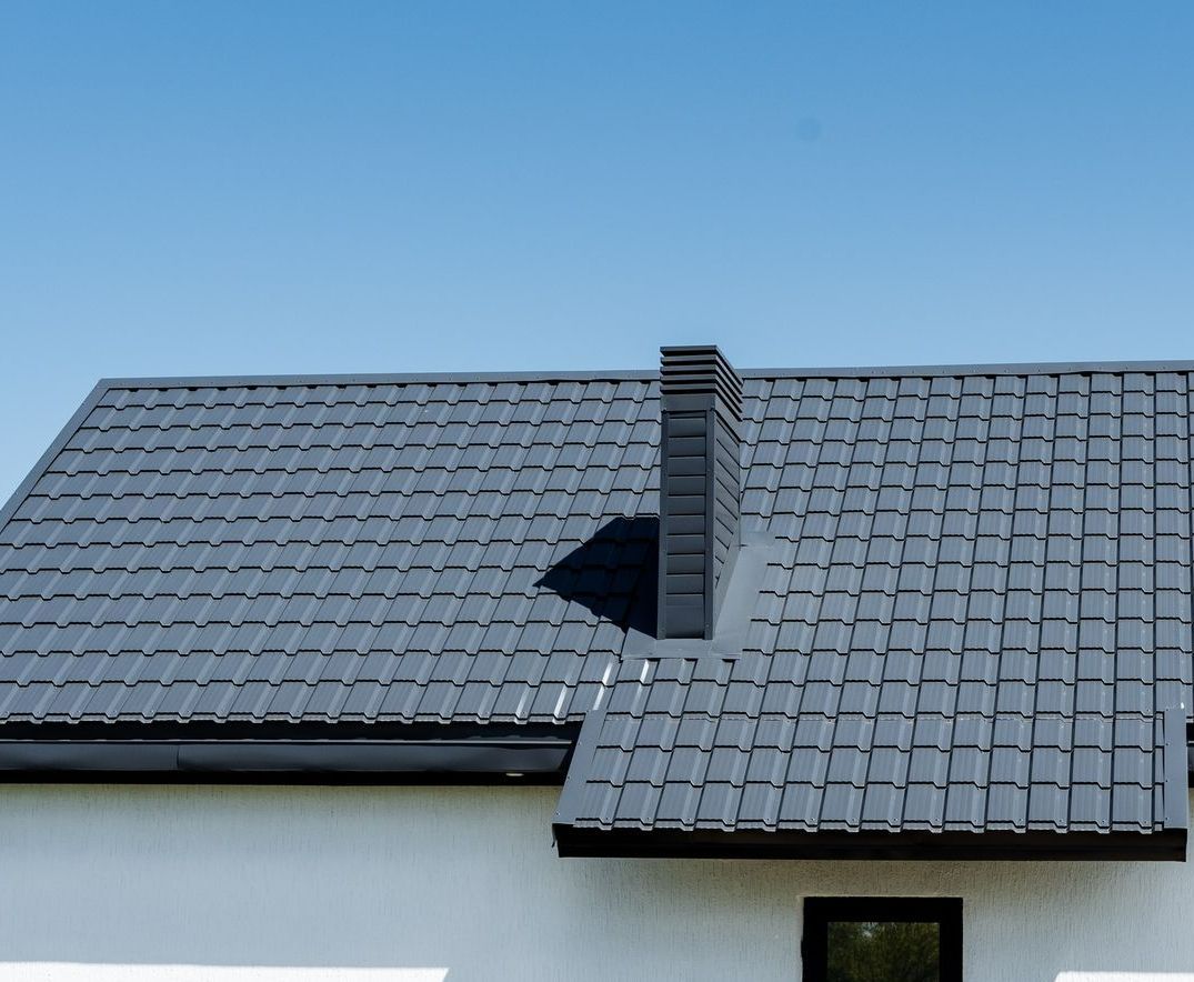 A White House With a Gray Roof and a Chimney — Apex Roofing Group in Yamba, NSW