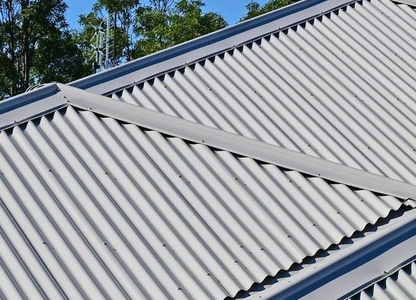 A White Corrugated Metal Roof With a Wind Turbine on Top of It — Apex Roofing Group in Yamba, NSW