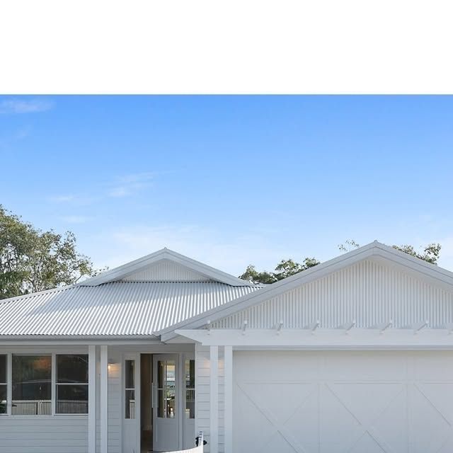 Modern white weatherboard home with a matching white corrugated metal roof and double garage, set against a clear blue sky. — Apex Roofing Group in Byron Bay, NSW