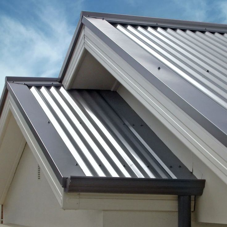 Close-up view of a modern residential roof with silver corrugated metal sheets and clean gutter lines, set against a blue sky.— Apex Roofing Group in Byron Bay, NSW