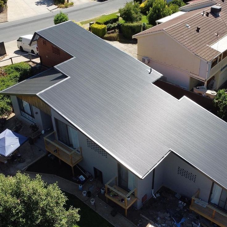 Aerial view of a residential home with a modern corrugated metal roof in a light grey color, featuring a unique stepped design and clean finish. — Apex Roofing Group in Byron Bay, NSW