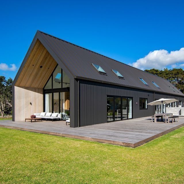 Modern black-clad home with matching black corrugated metal roofing, large glass windows, and a minimalist gable design blending contemporary and industrial styles.— Apex Roofing Group in Grafton, NSW