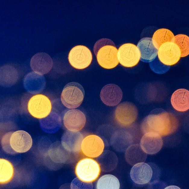 Blurred city lights at night in blue, yellow, and orange bokeh.
