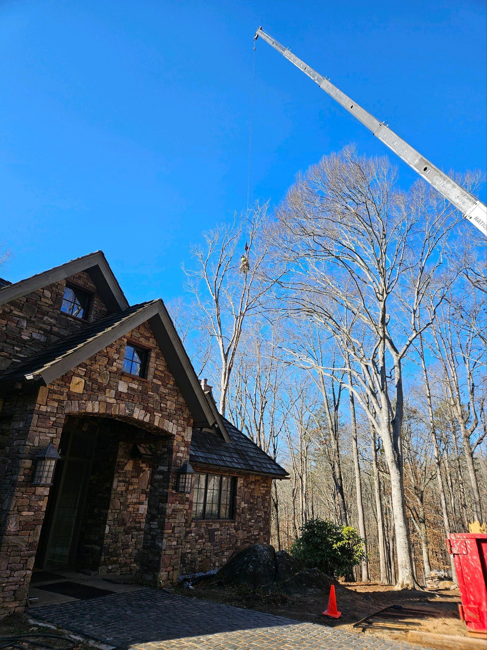 Stone house with a tall tree and crane against a blue sky.