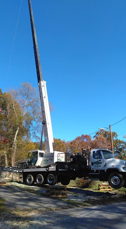 Crane truck with extended boom against a clear blue sky, likely for construction or tree removal.