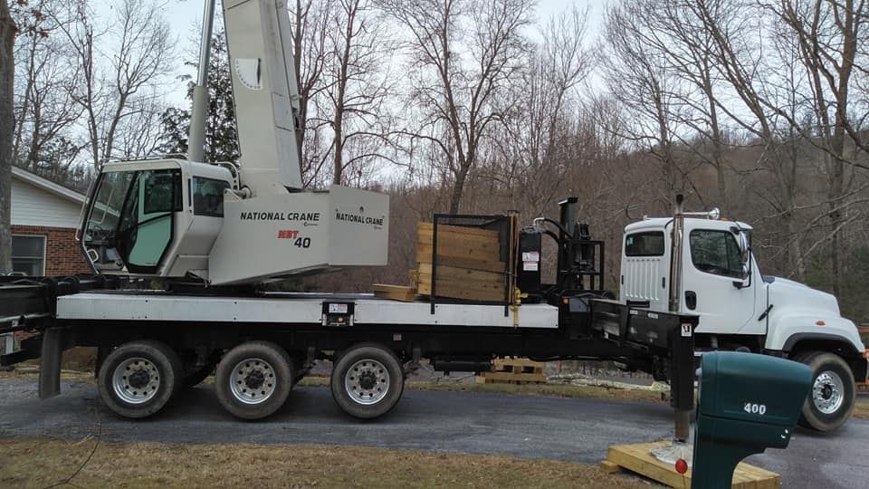 White crane truck parked in a residential area. The crane's arm is raised.