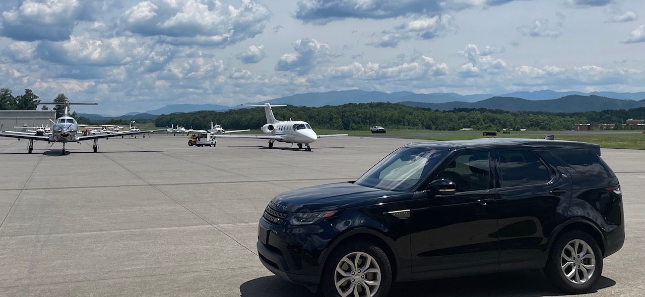 a black suv is parked on the tarmac of an airport .