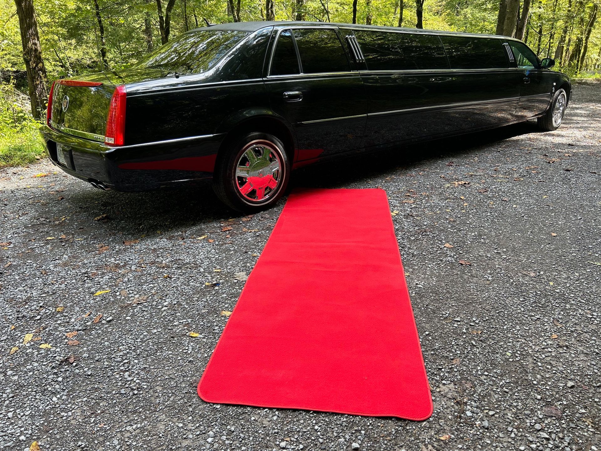 a black limousine is parked next to a red carpet .