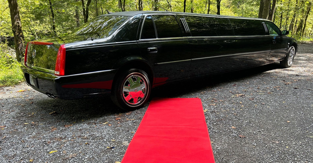 a black limousine is parked next to a red carpet .