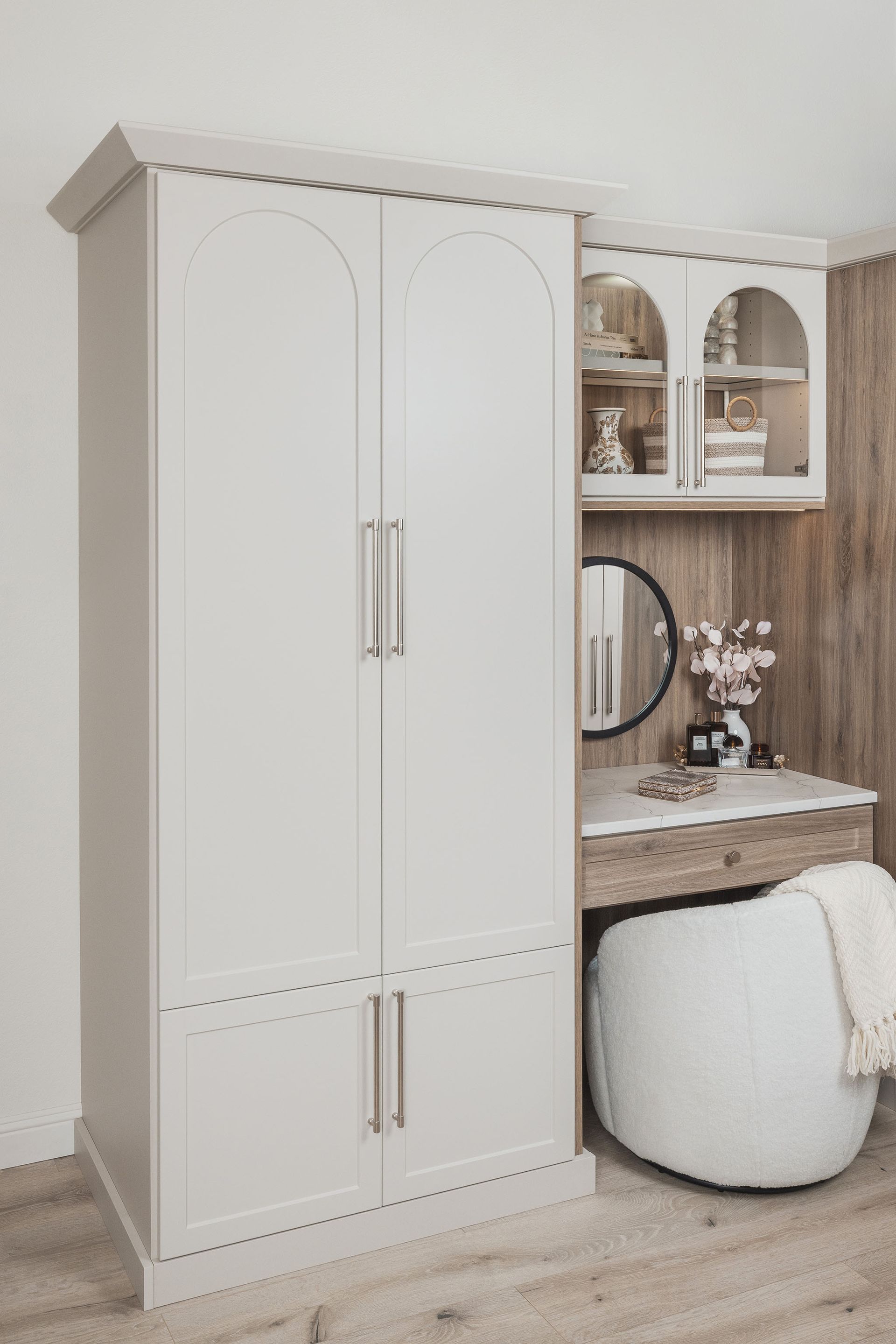 White wardrobe and vanity desk with mirror and chair in a light, modern bedroom nook