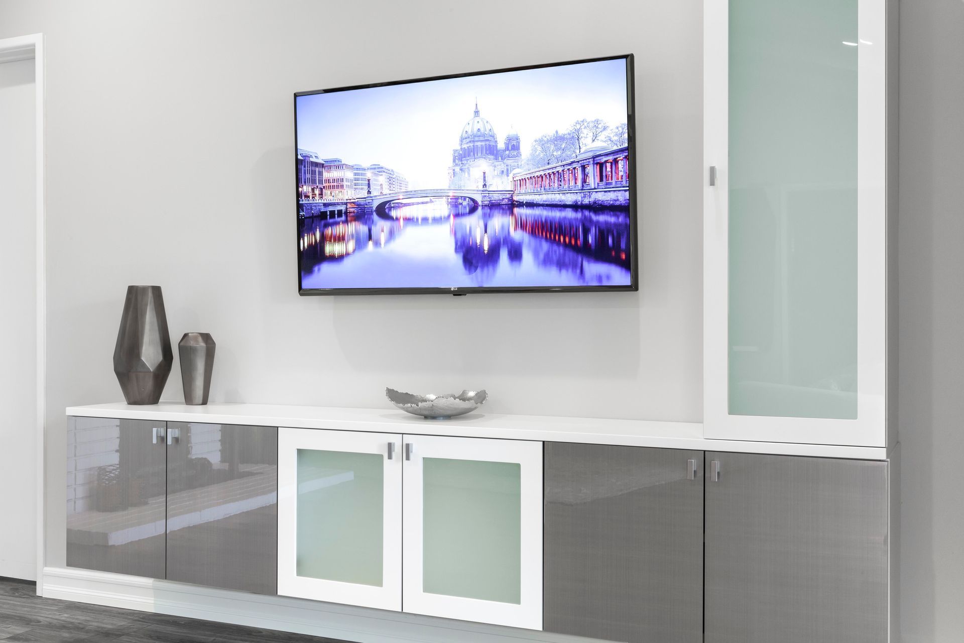 Modern living room with wall-mounted TV, white media cabinet, and decorative vases