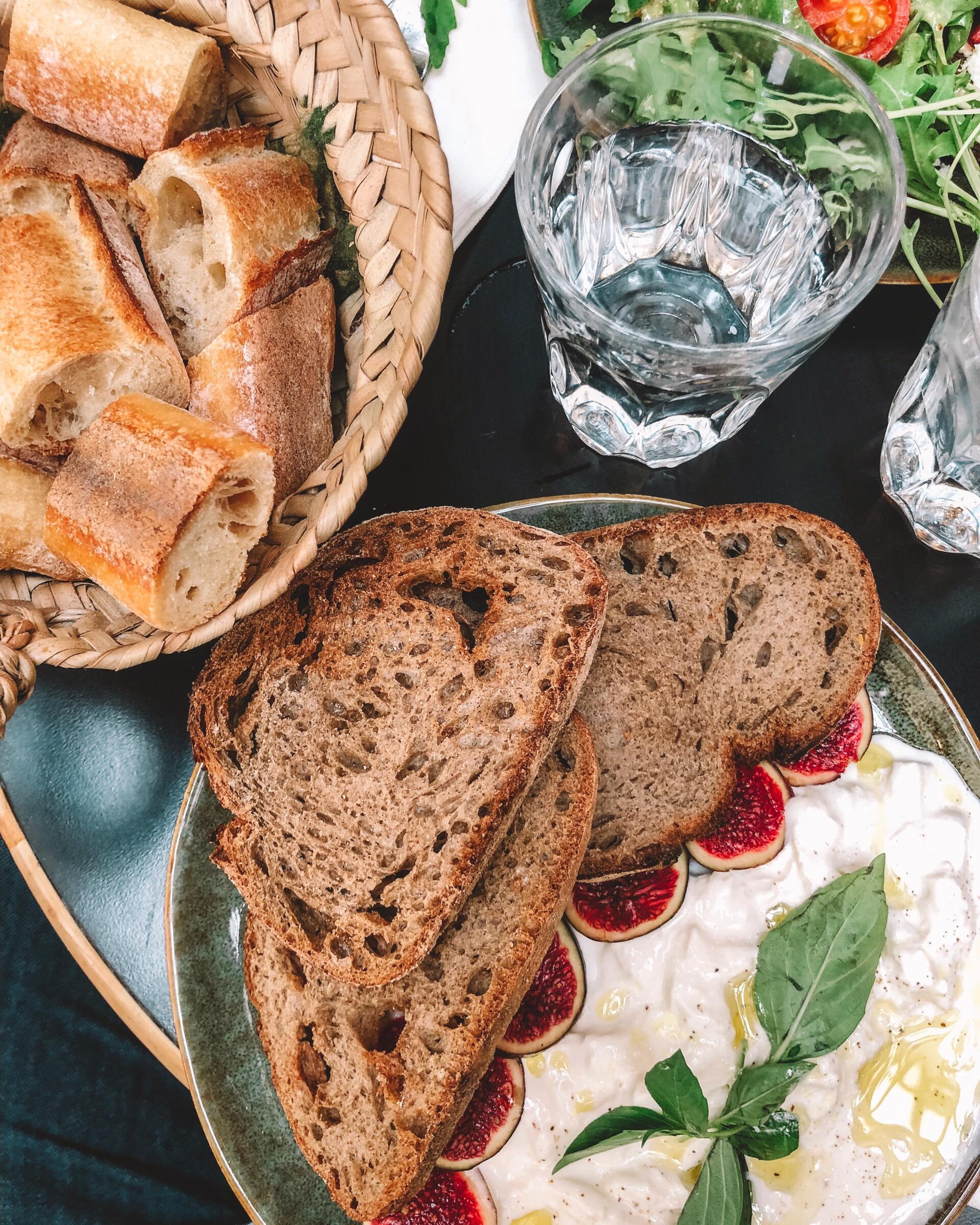 Een bord met eten, een mandje brood en een kom water op tafel.