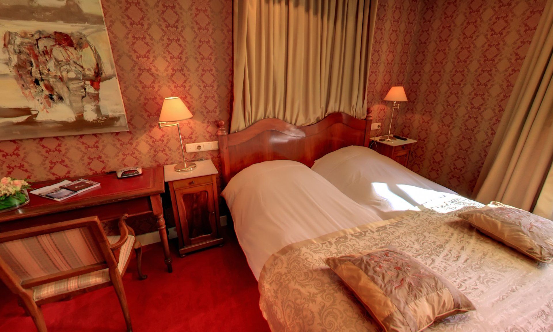 Een hotelkamer met twee bedden, een bureau en een stoel.