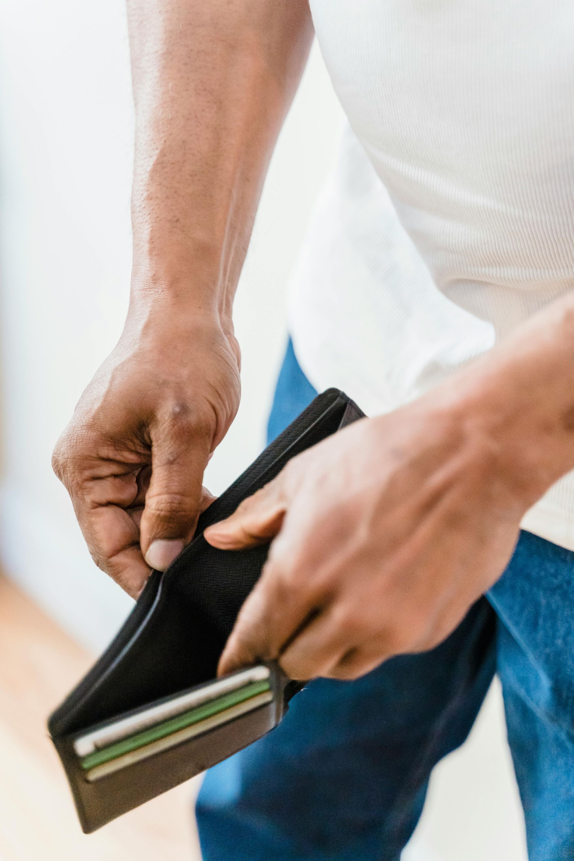 Person opening an empty black wallet, revealing a few cards.