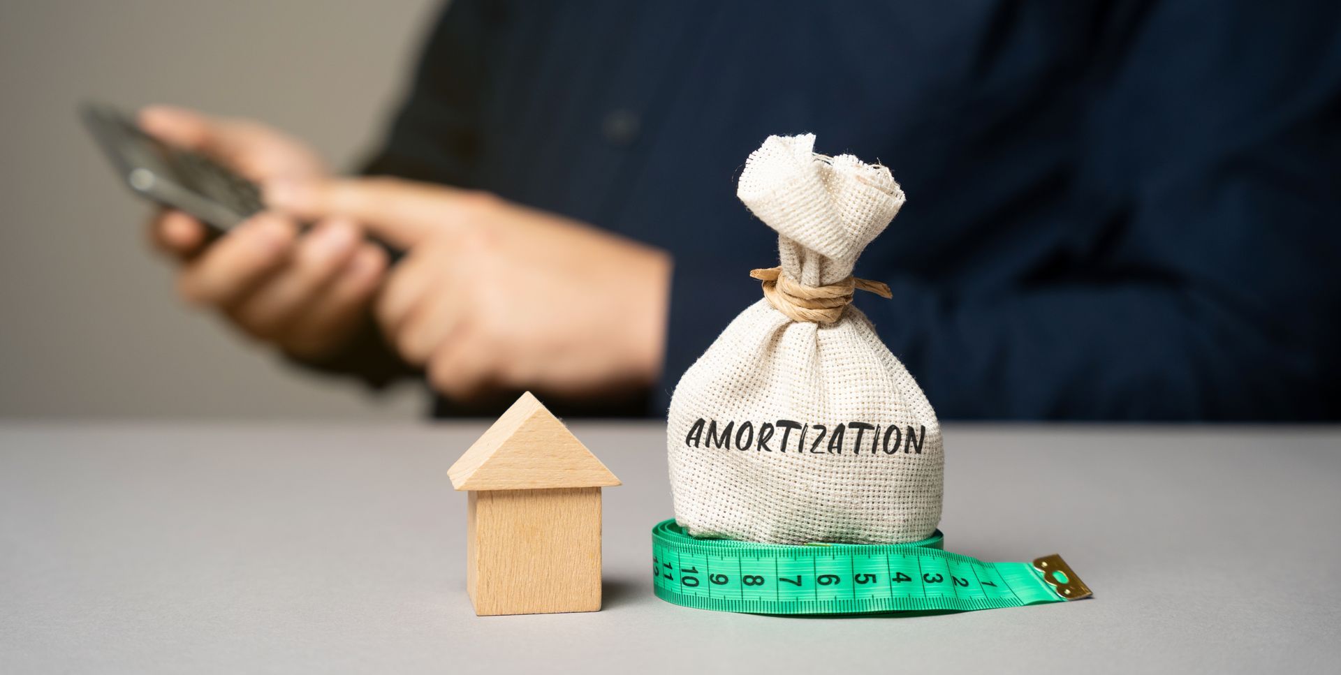 A person using a phone, a small wooden house, and a sack labeled