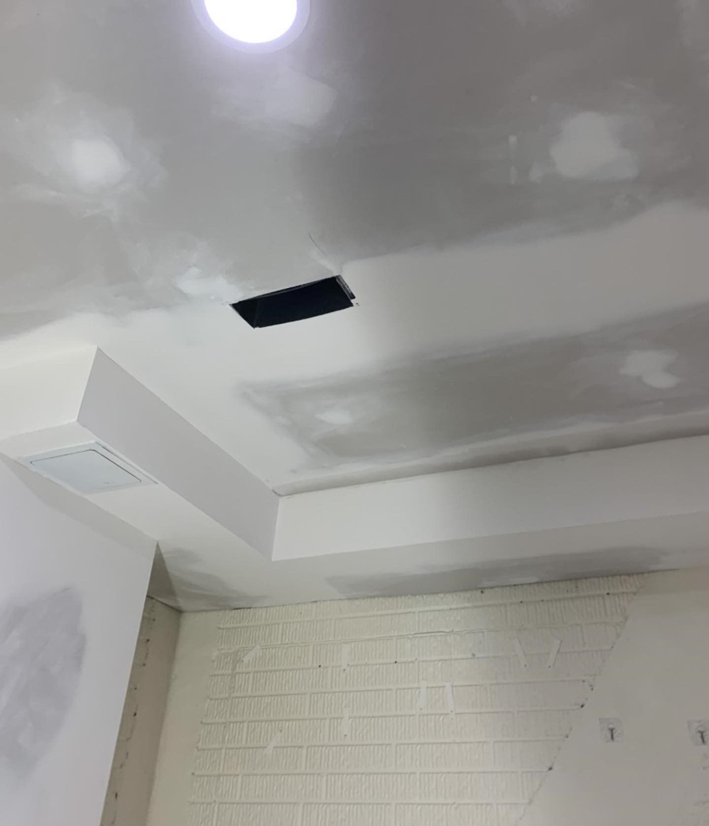A ceiling with a hole in it and a light on it.
