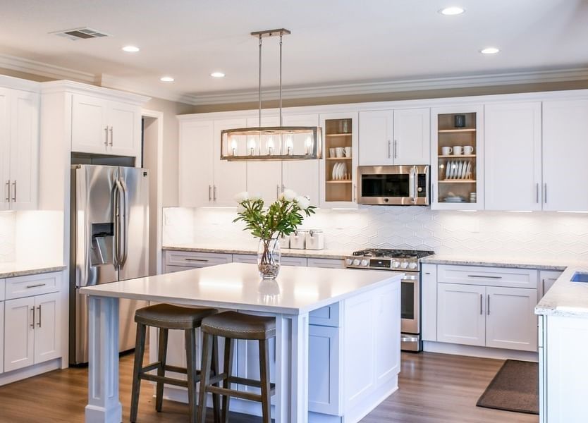 A kitchen with white cabinets , stainless steel appliances , and a large island.
