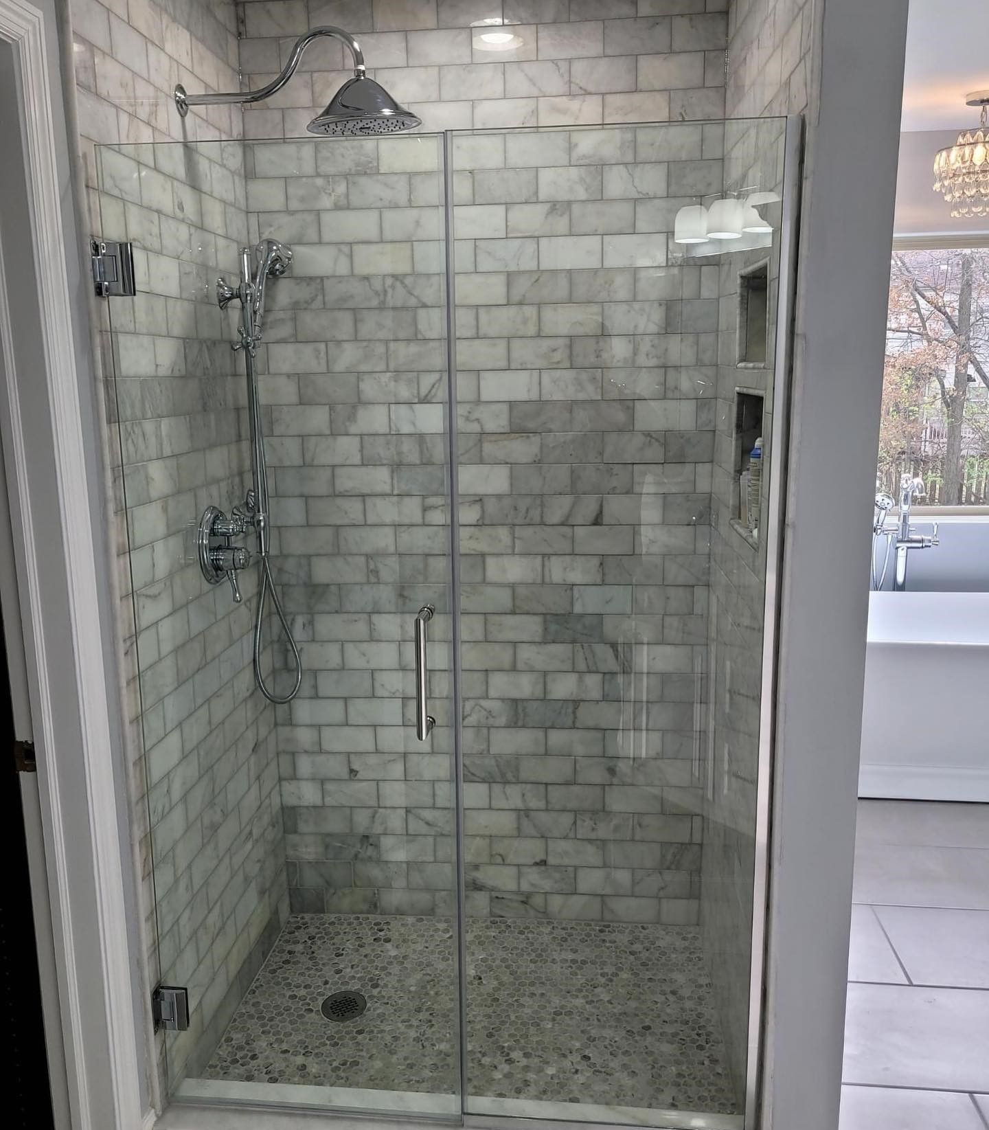 A bathroom with a walk in shower with a glass door