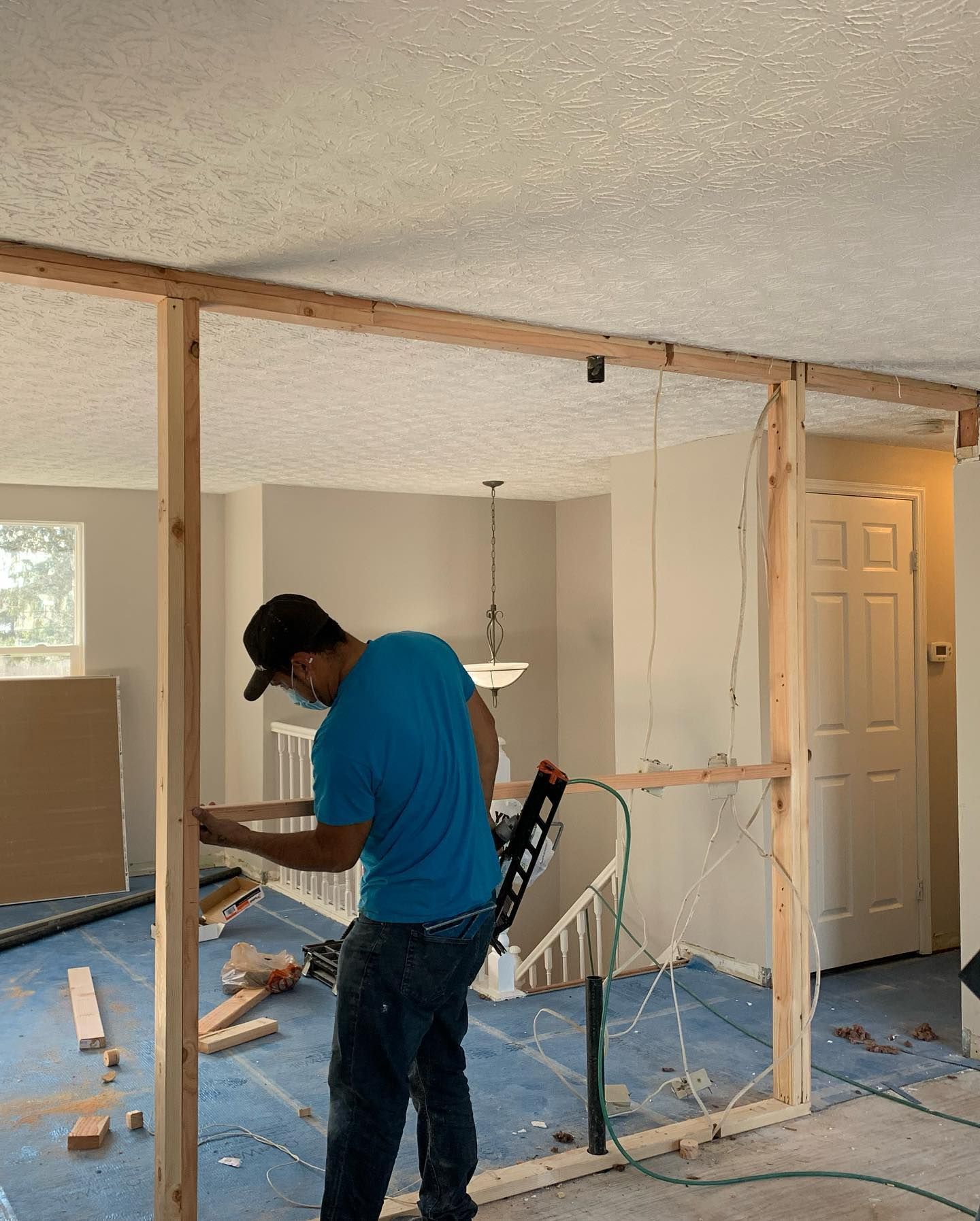 A man in a blue shirt is working on a wall in a room.