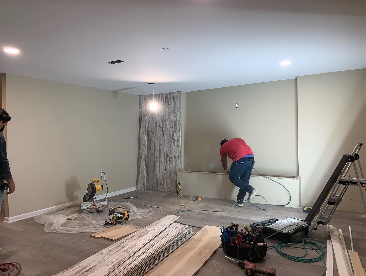 A man in a red shirt is working on a wall in a room.