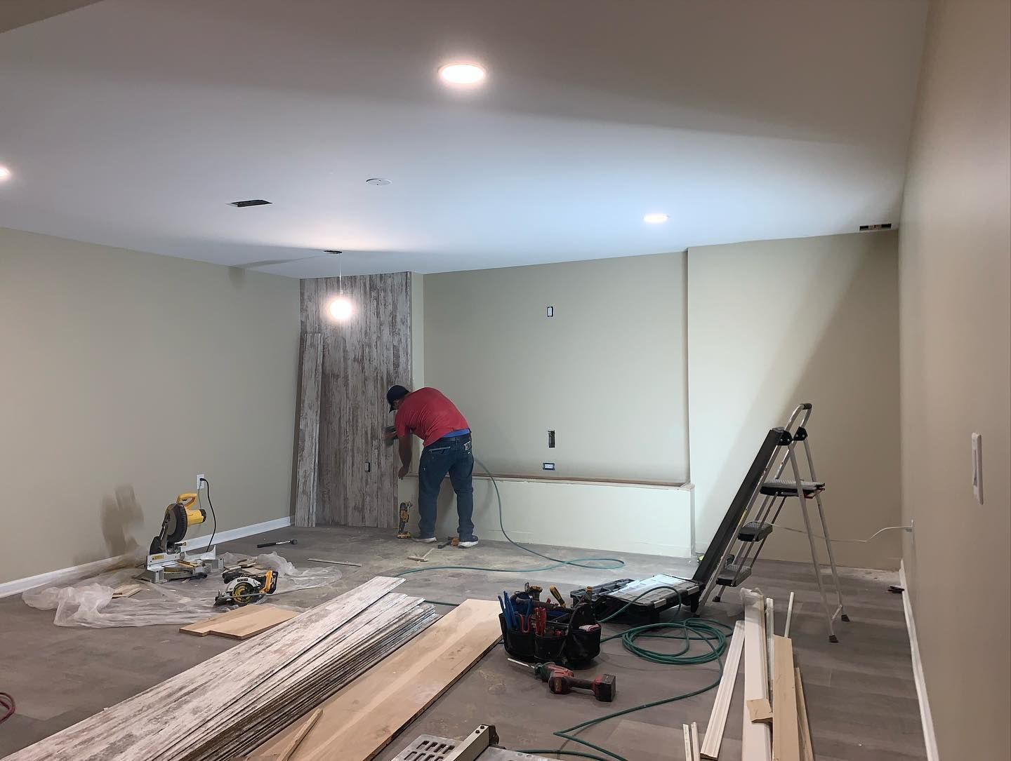 A man is working on a wall in a room.