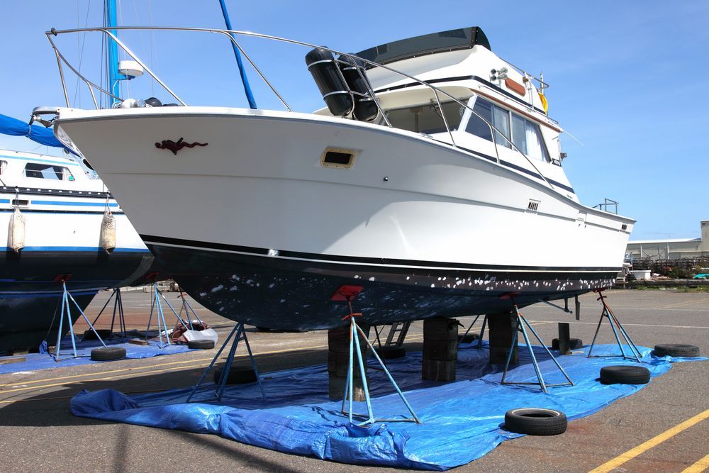 White boat on stands in a boatyard, blue tarp below the hull, sunny day — Adettra in Tuncurry, NSW