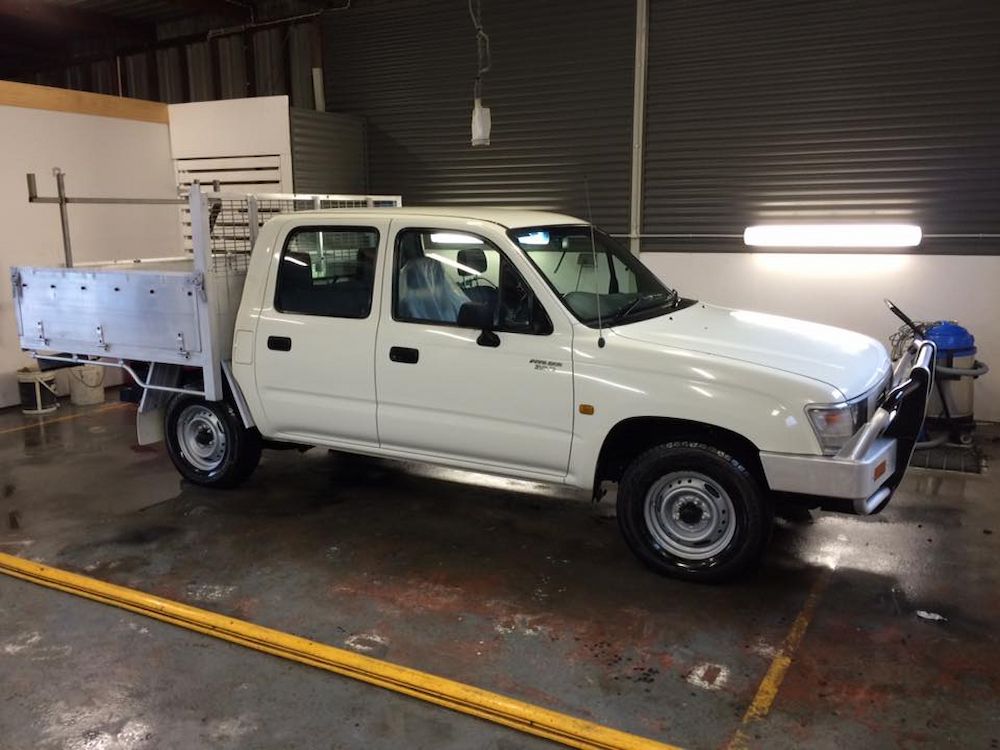 A White Truck With a Tray on the Back is Parked in a Garage — Adettra in Tuncurry, NSW