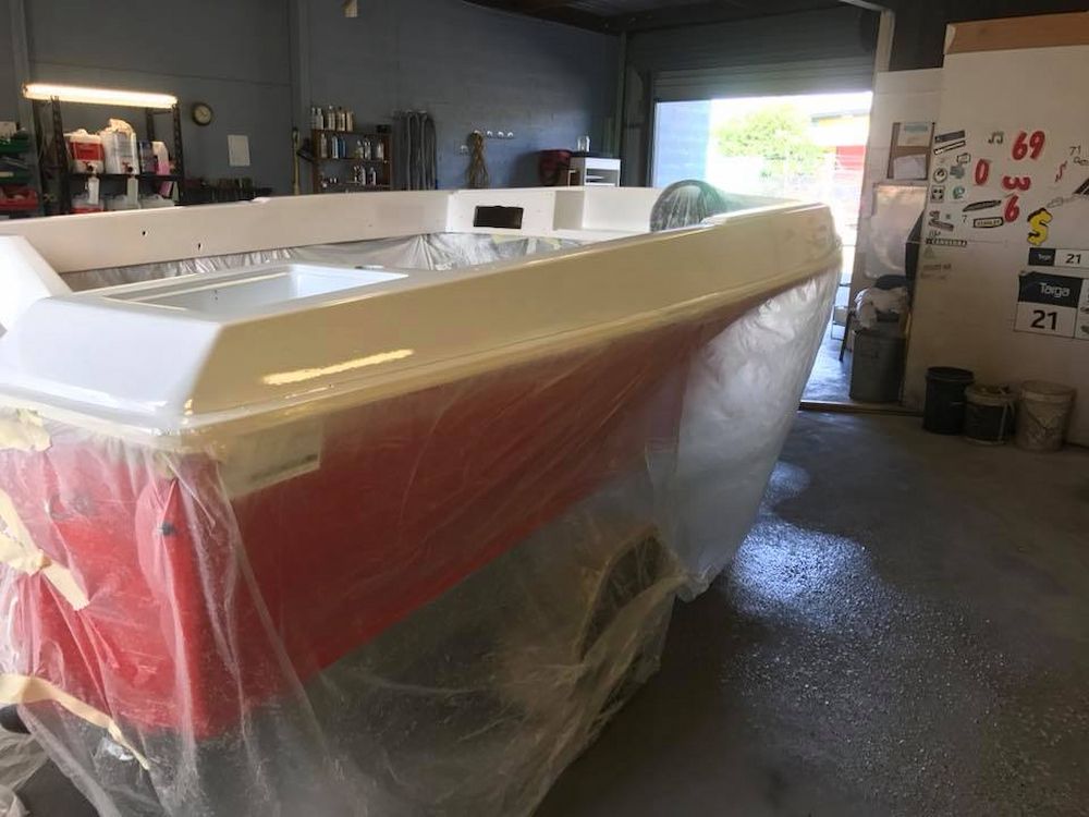 A Red and White Boat is Wrapped in Plastic in a Garage — Adettra in Tuncurry, NSW