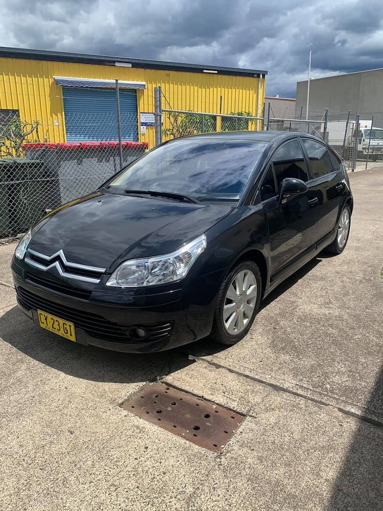 A Black Car is Parked in front of a yellow building — Adettra in Tuncurry, NSW