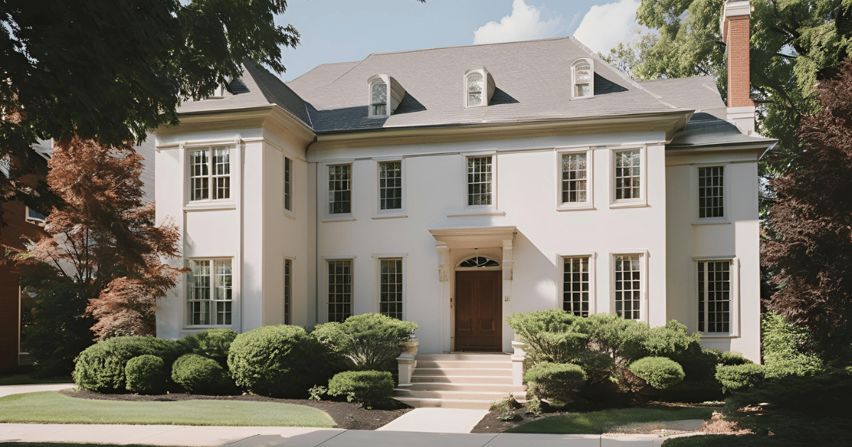 A large white house with a lot of windows and bushes in front of it