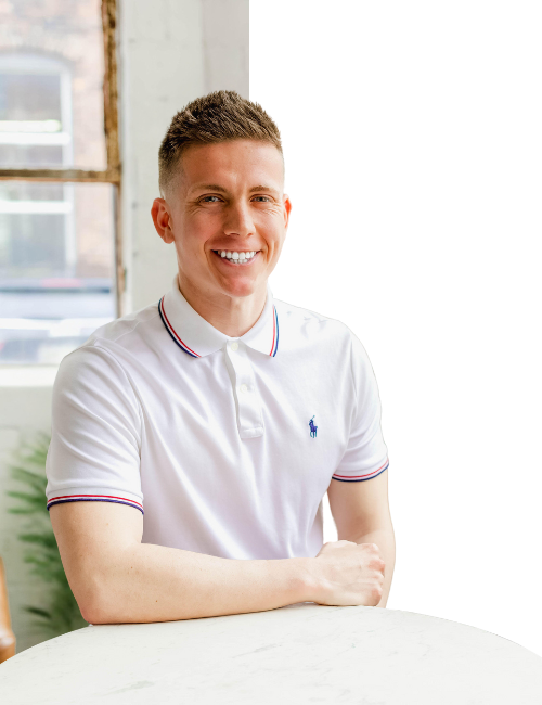 A man in a white polo shirt is sitting at a table.
