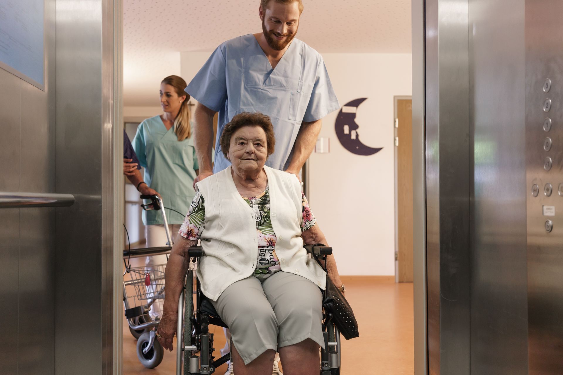 Nurses helping elderly man and woman in wheelchair getting into the elevator. Nurses helping elderly man and woman in wheelchair getting into the elevator.