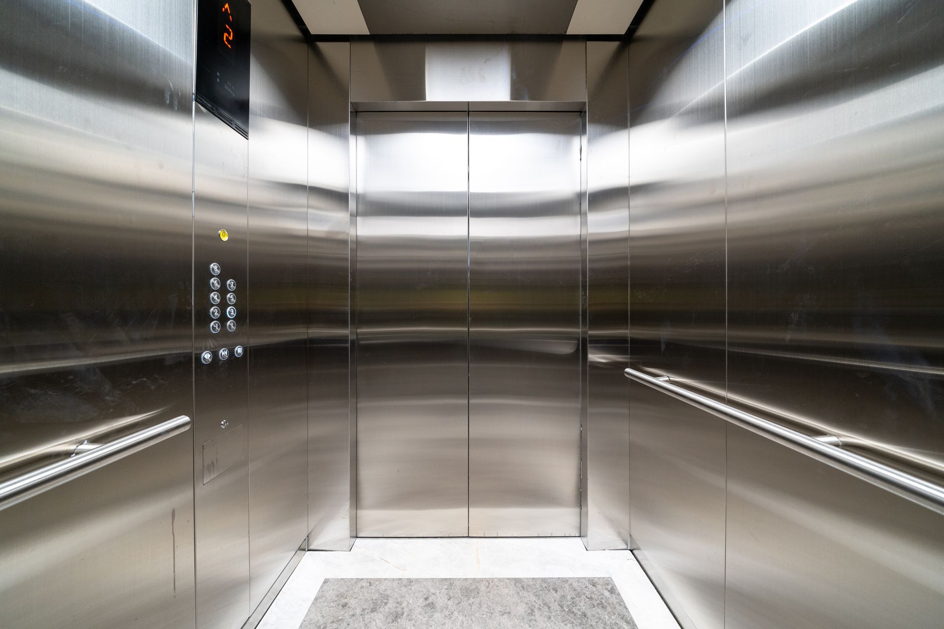 Inside a sleek stainless steel elevator with a digital floor display and controls.