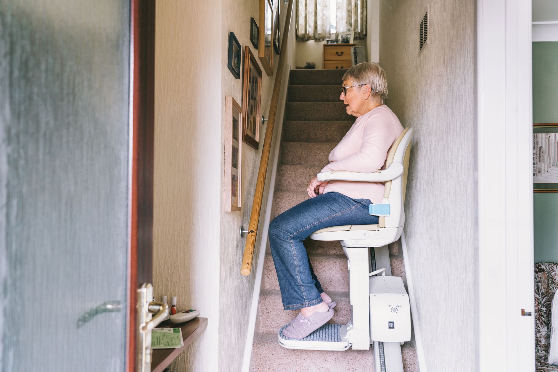 Senior woman using an automatic stair lift on a staircase at her home.