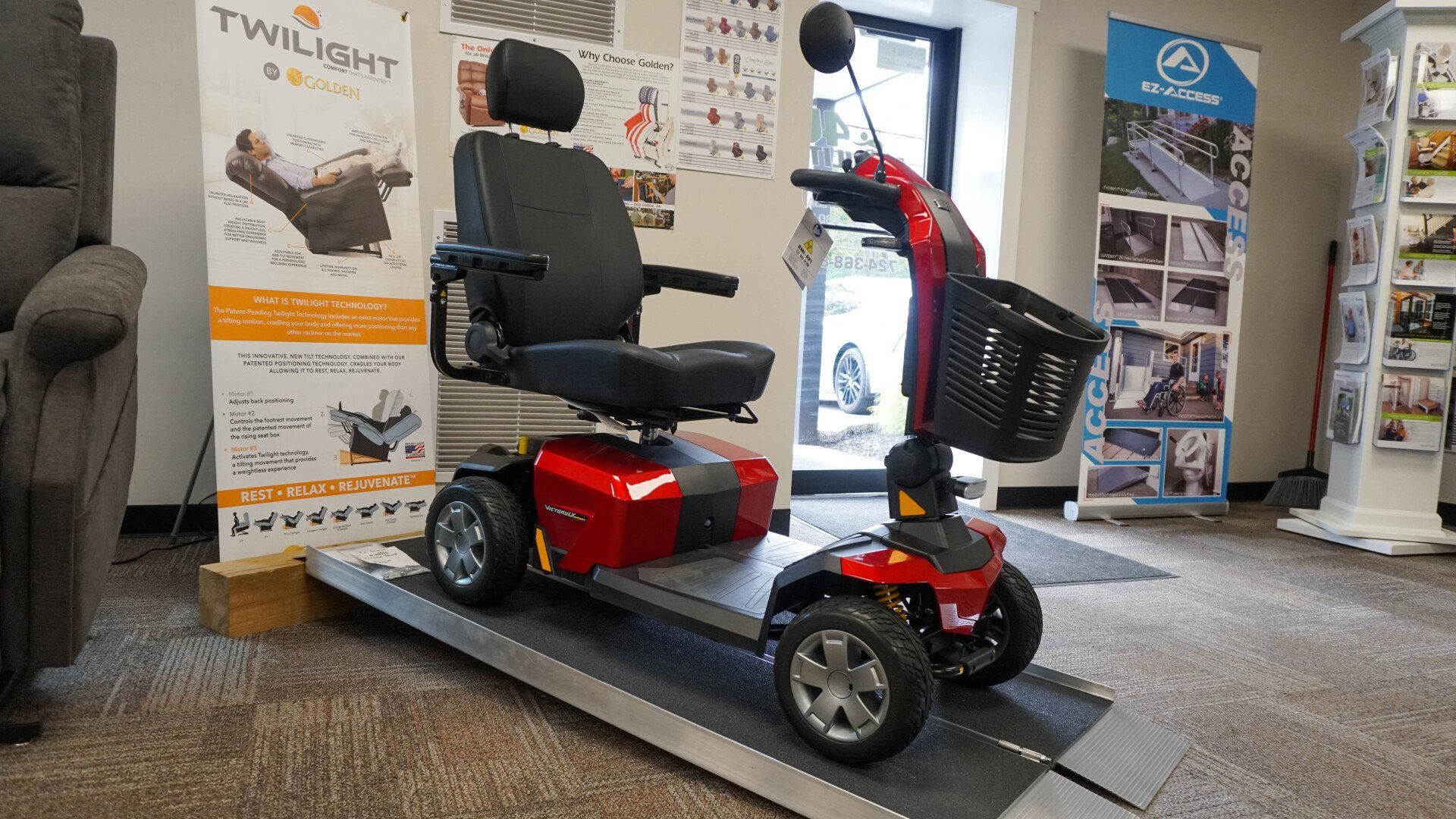 A red mobility scooter is sitting on a ramp in a room.