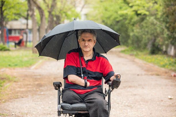 Man in a wheelchair holding an umbrella, looking to find a motor scooter dealer for mobility.